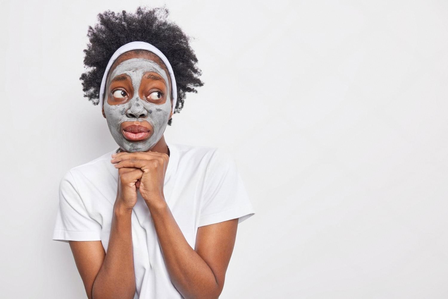 Young woman with a clay anti-aging mask on her face at home